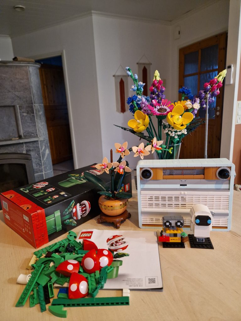 Keittiön saarekkeelle on aseteltu erilaisia koottuja Legoja: turkoosi retro radio, värikäs villikukkakimppu, Wall-E ja Eve - hahmot, ruukussa oleva orkidea ja kokoamaton piraijakasvi.